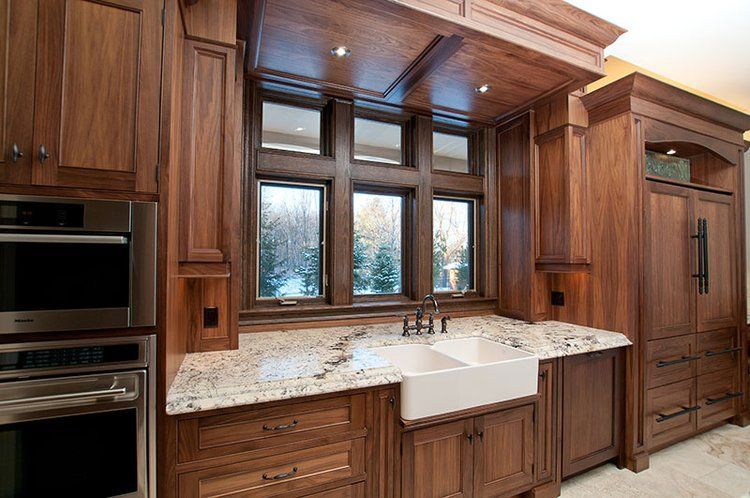 A kitchen with wooden cabinets , granite counter tops , stainless steel appliances and a sink.