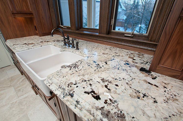 A kitchen with a sink and granite counter tops.
