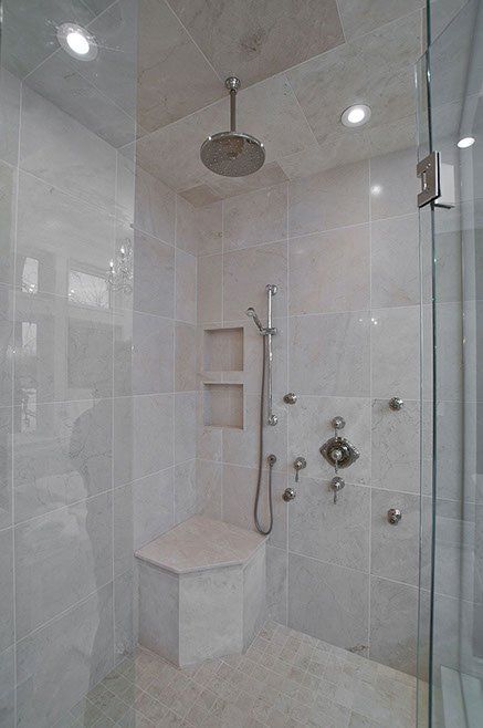 A walk in shower with a bench and a shower head.