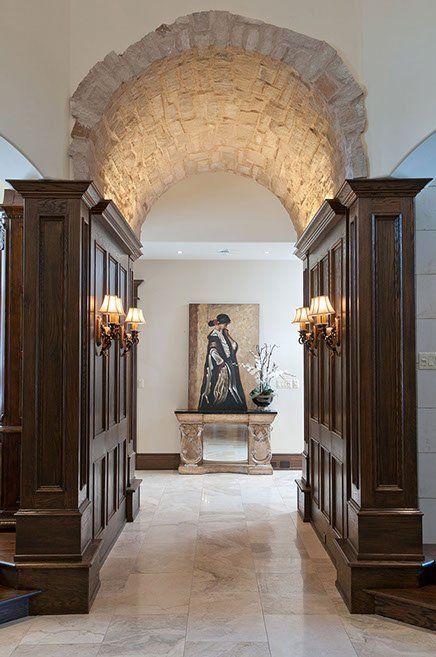A hallway with a stone archway and a painting on the wall.