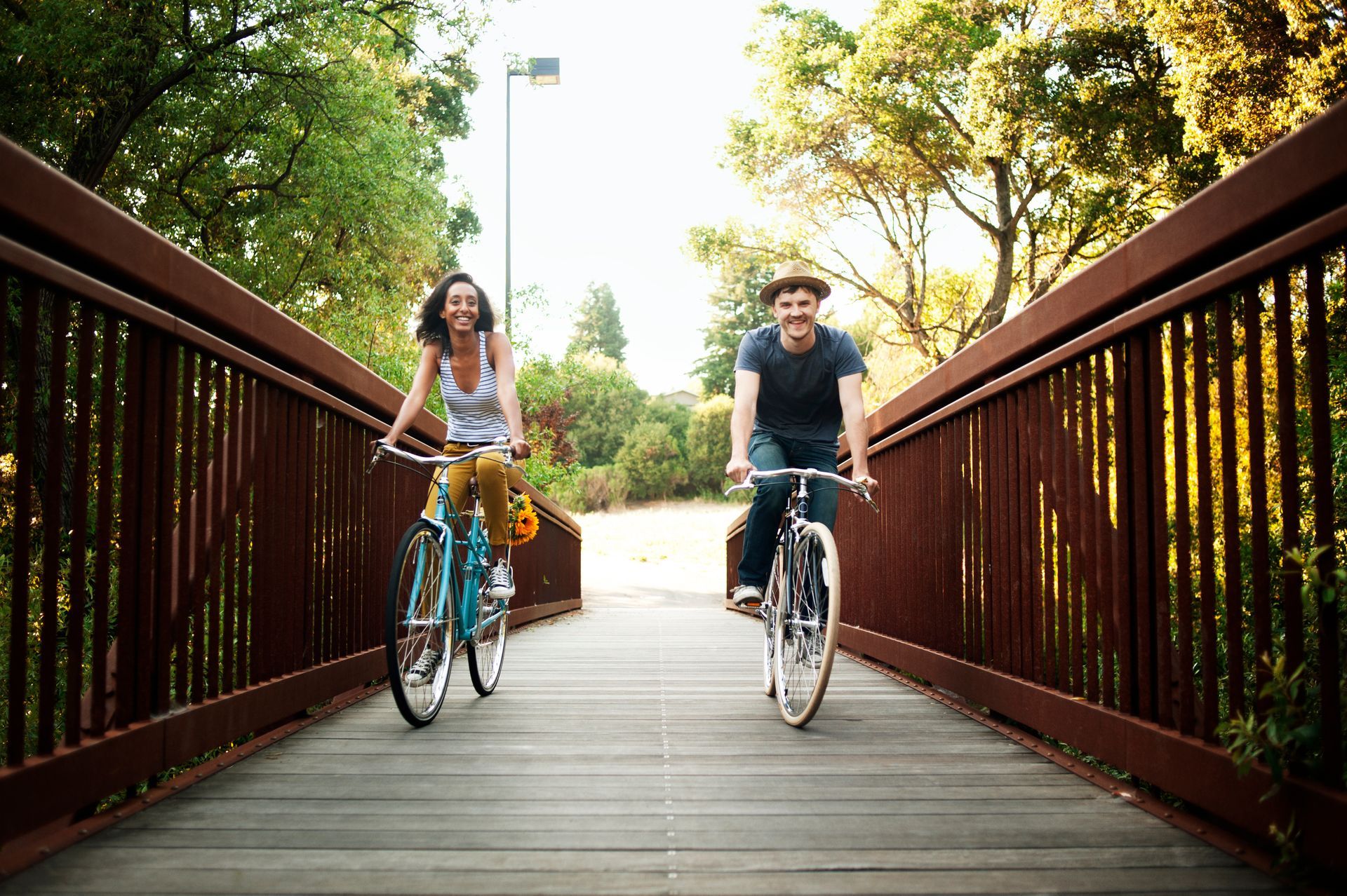 A man and a woman are riding bicycles on a bridge.