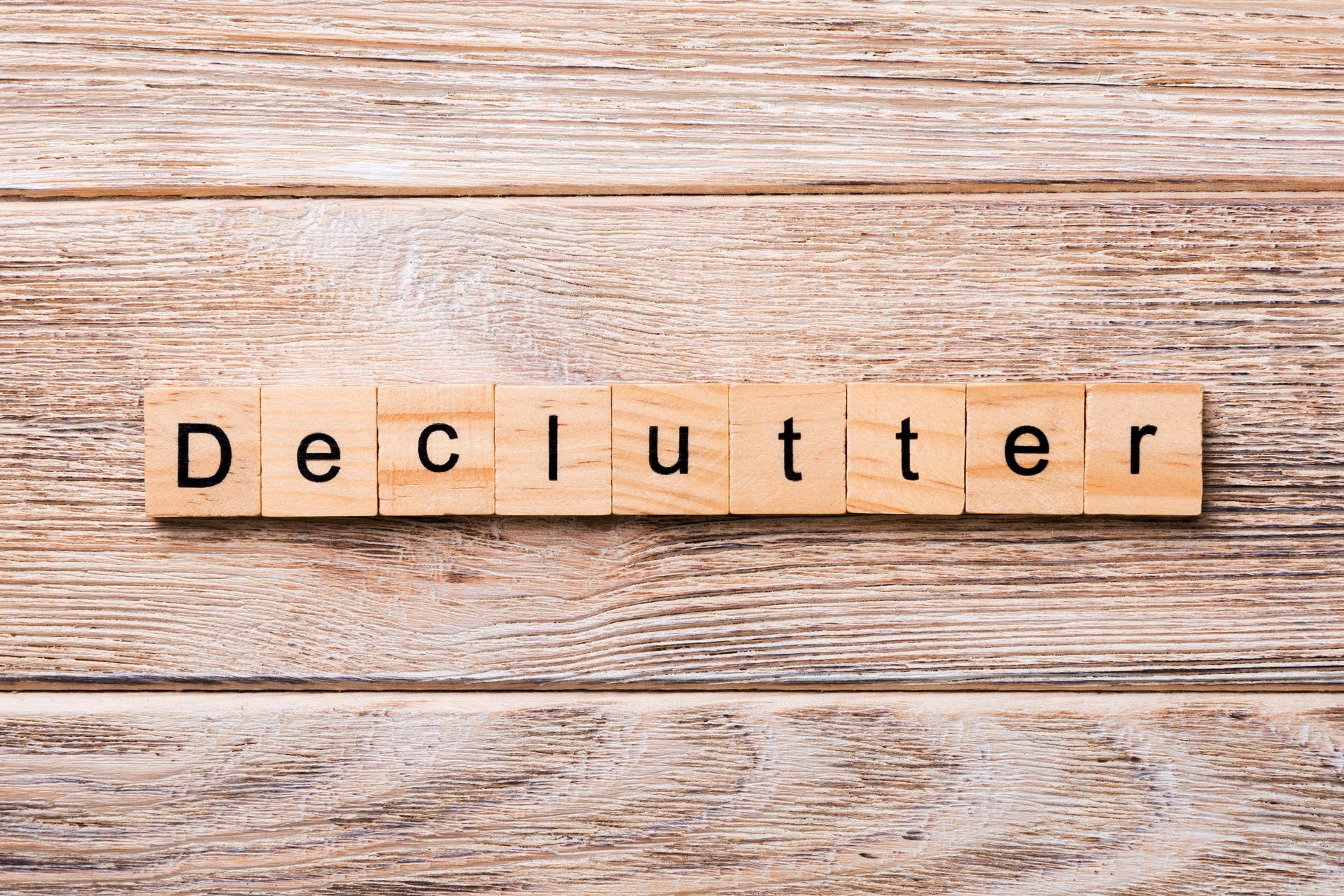 The word declutter is written in wooden blocks on a wooden table.