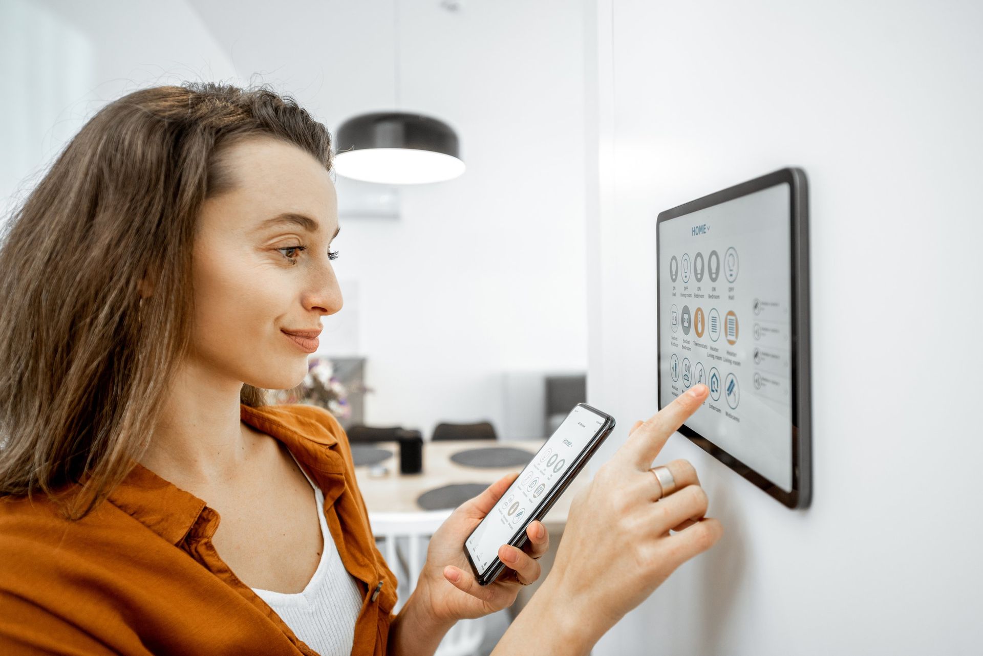 A woman is using a smart device to control her home.