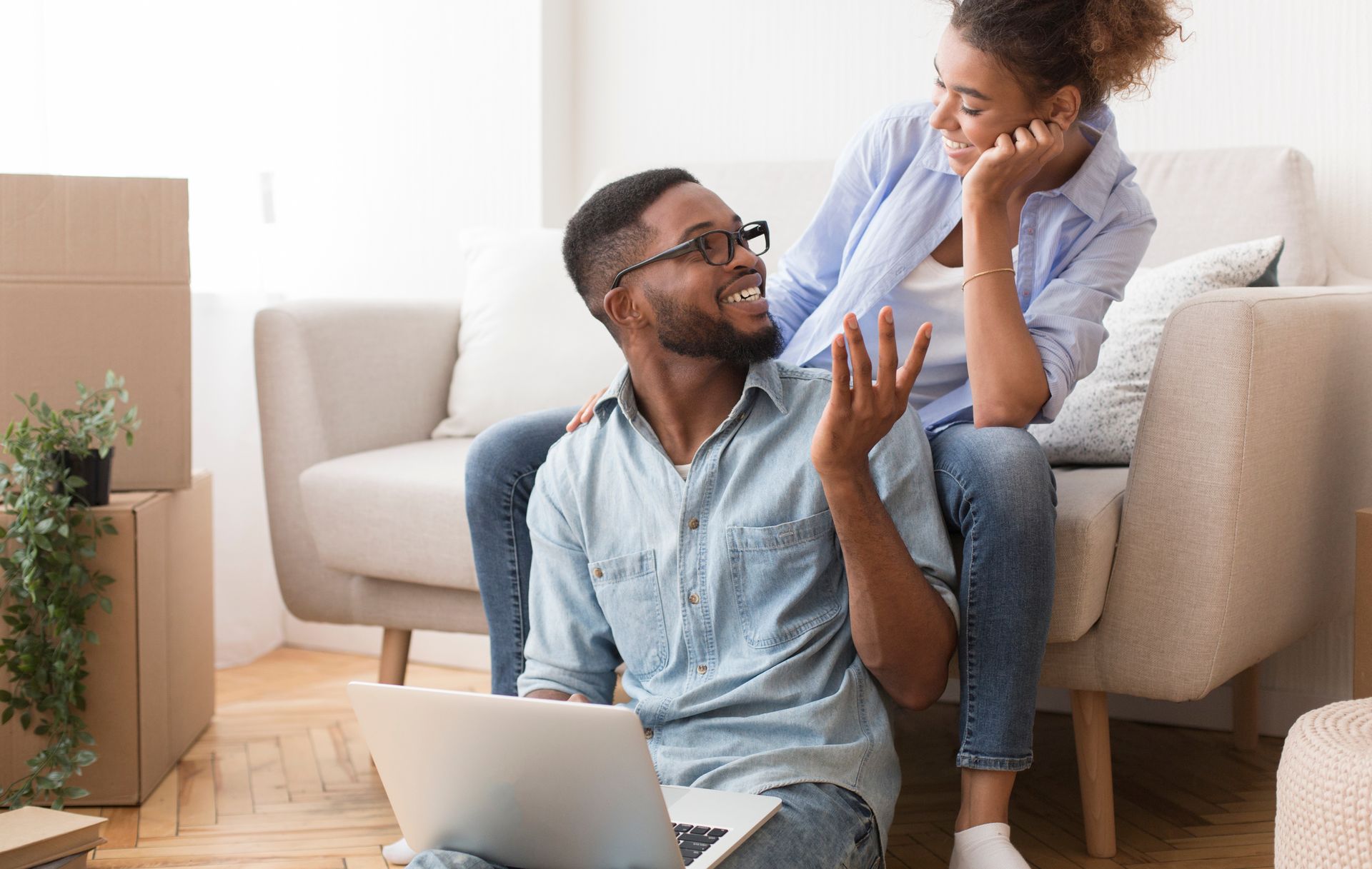 A man and a woman are sitting on a couch with a laptop.