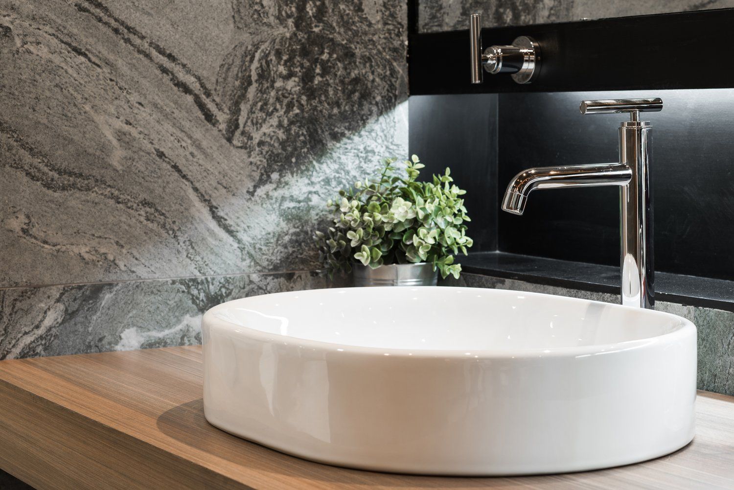 A bathroom sink is sitting on top of a wooden counter.