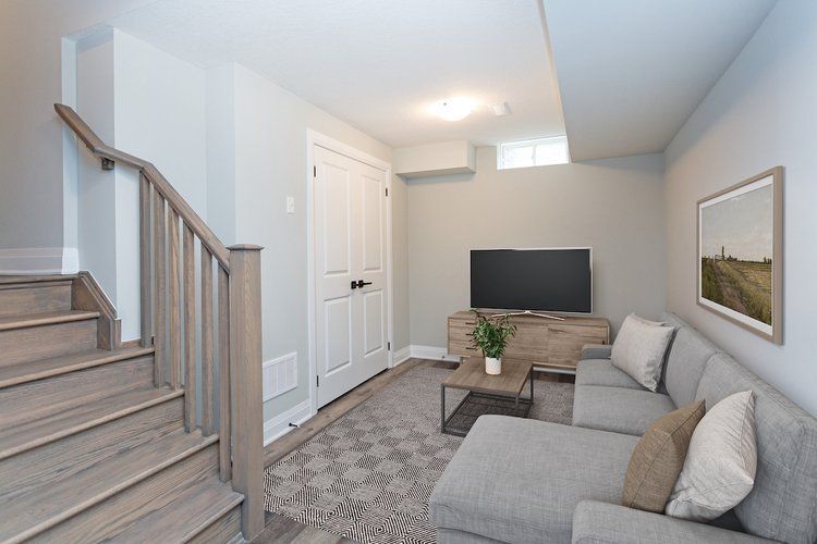 A living room with a couch , television , and stairs.