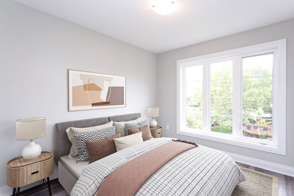 A bedroom with a bed , nightstands , lamps and a large window.