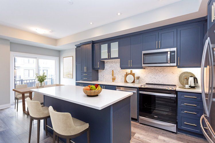 A kitchen with blue cabinets , stainless steel appliances , and a large island.