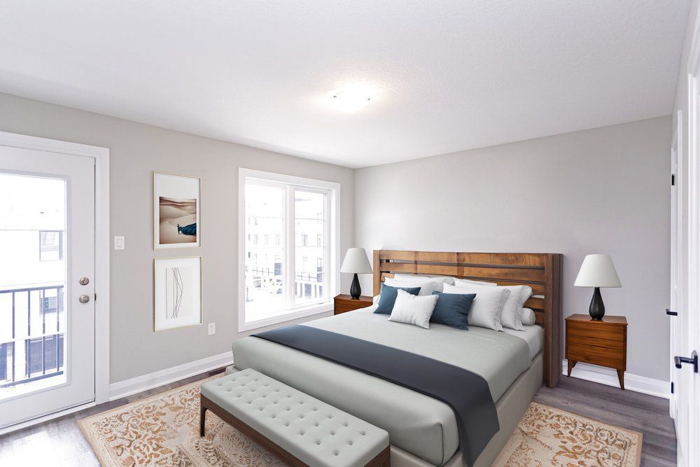 A bedroom with a king size bed , nightstands , lamps and a balcony.