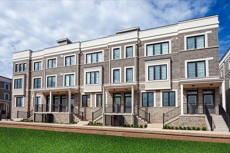 A large brick building with a lot of windows is sitting on top of a lush green field.