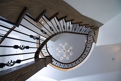 Looking up at a spiral staircase with a chandelier hanging from the ceiling.