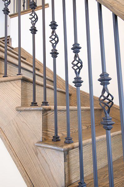 A close up of a wrought iron railing on a wooden staircase