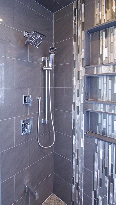 A shower with a stainless steel shower head and a glass door.