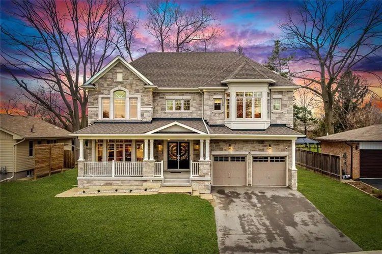A large house with a large driveway and a sunset in the background.