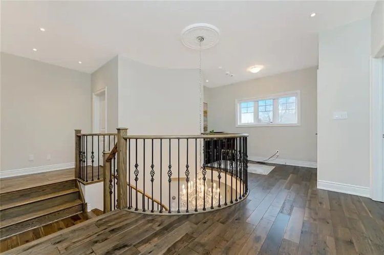 There is a staircase in the middle of the room with a chandelier hanging from the ceiling.