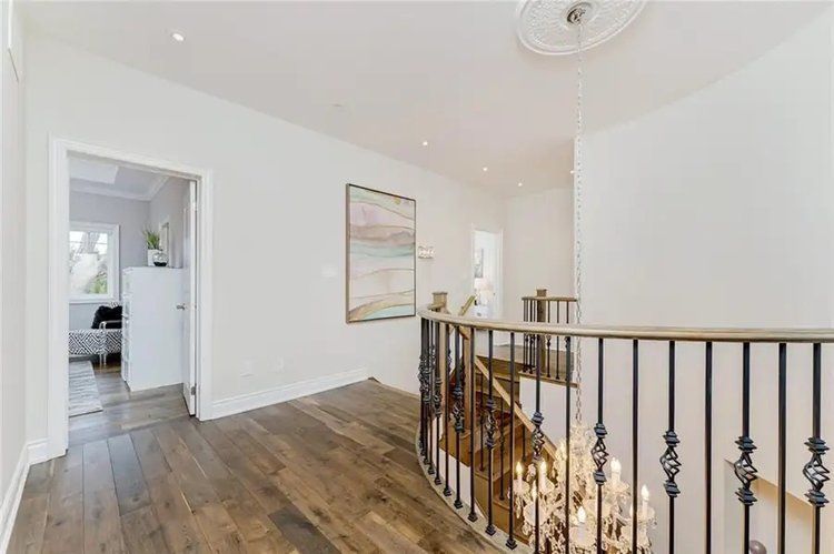 A hallway with a staircase and a chandelier in a house.