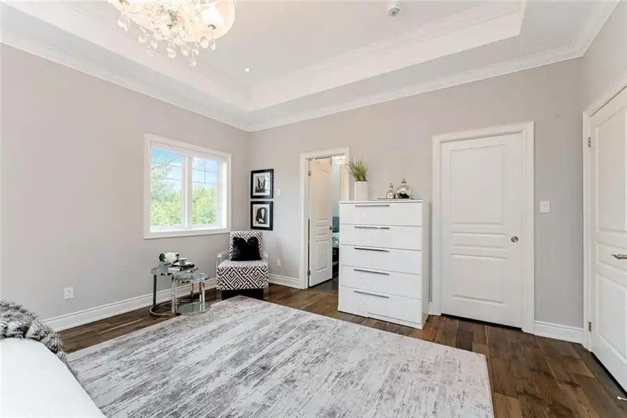 A bedroom with a bed , dresser , chair and rug.