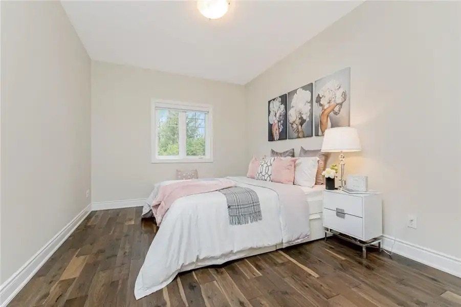 A bedroom with two beds , a nightstand , a lamp and a window.