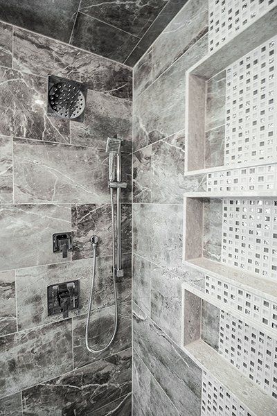 A black and white photo of a shower with a shower head and shelves.