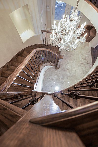 A wooden spiral staircase with a chandelier hanging from the ceiling.