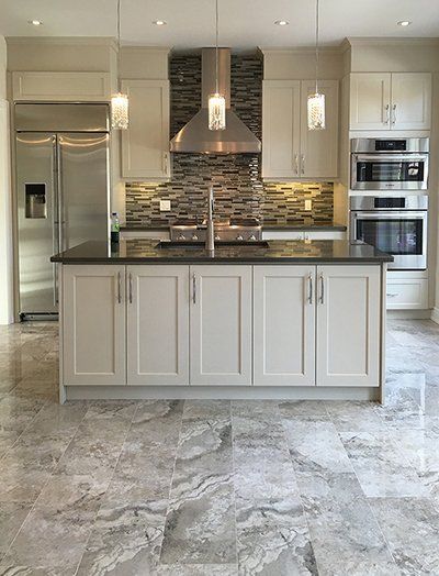 A kitchen with white cabinets , granite counter tops , stainless steel appliances and a large island.