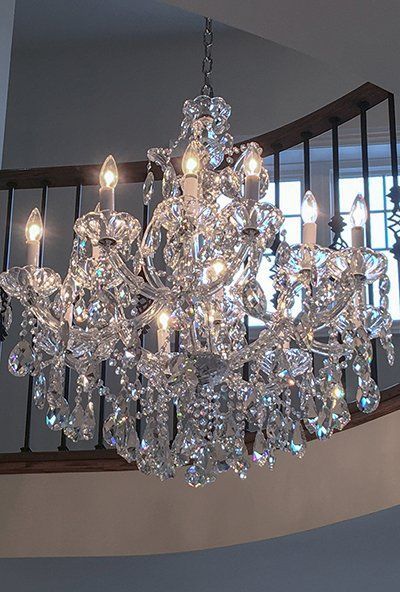 A large chandelier is hanging from the ceiling above a staircase.