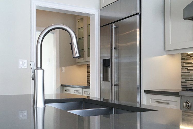 A kitchen with a stainless steel refrigerator and a sink