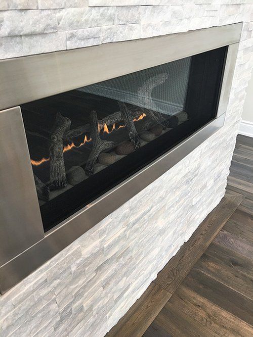 A fireplace is built into a white brick wall.