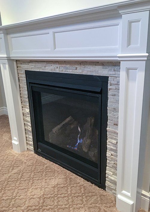 A fireplace with a white mantle and a brick wall in a living room.