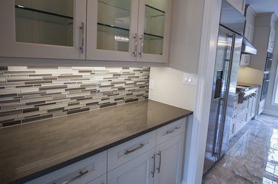 A kitchen with white cabinets , stainless steel appliances , and a tiled backsplash.