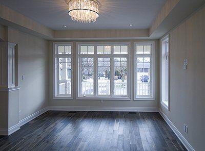 An empty living room with a lot of windows and a chandelier.