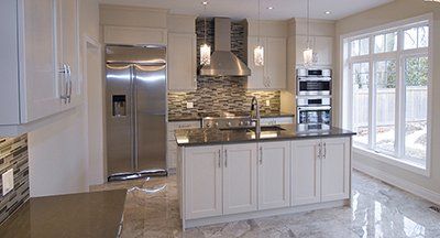 A kitchen with white cabinets , stainless steel appliances and a large island.