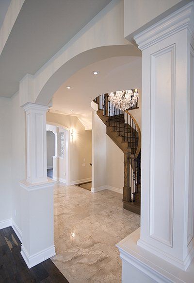 A hallway with columns and a staircase in the background
