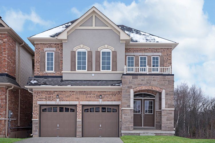 A large brick house with two garage doors and a balcony