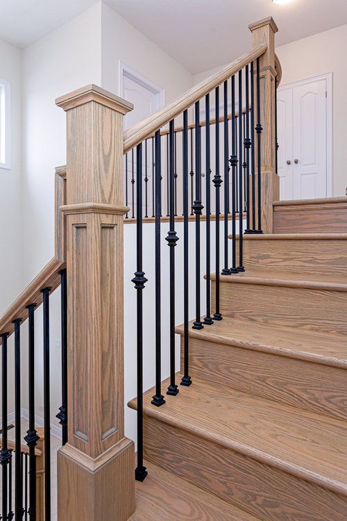 A wooden staircase with a black railing in a house.
