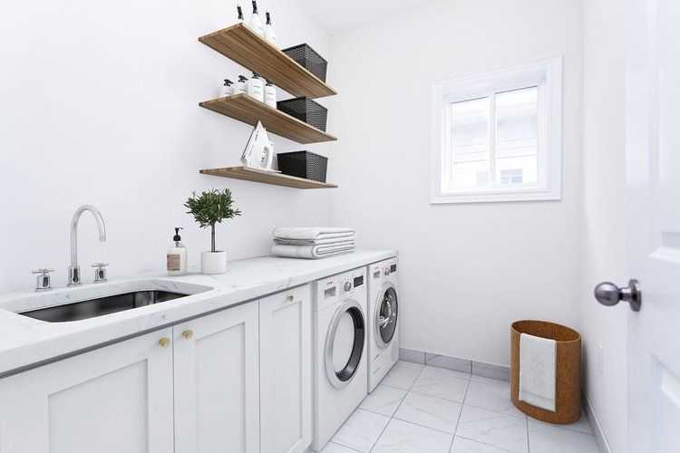 A laundry room with a sink , washer and dryer , and shelves.