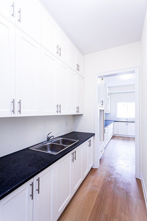 A kitchen with white cabinets and black counter tops