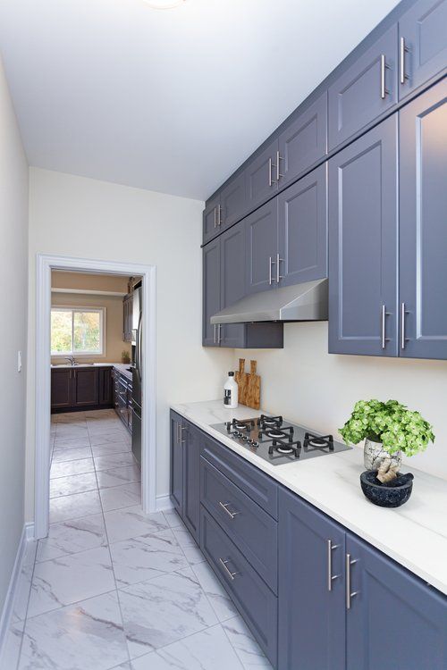 A kitchen with gray cabinets and white counter tops