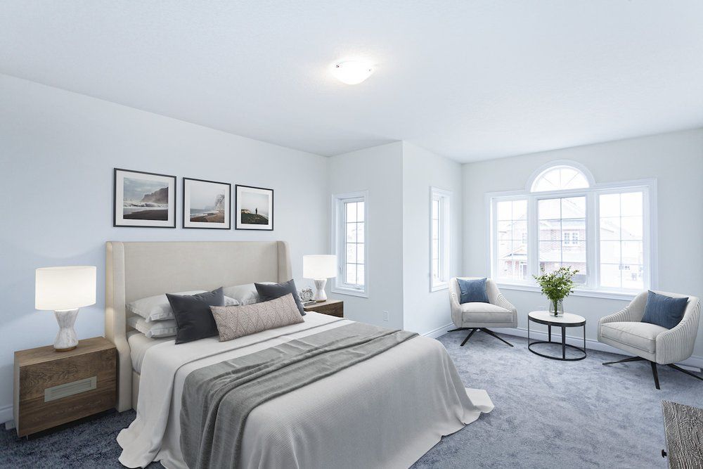 A bedroom with a bed , chairs , nightstands and a table.