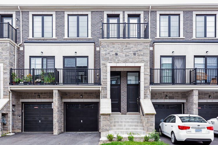 A white car is parked in front of a row of houses.