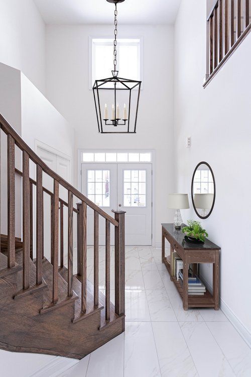 A hallway with a wooden staircase and a mirror.