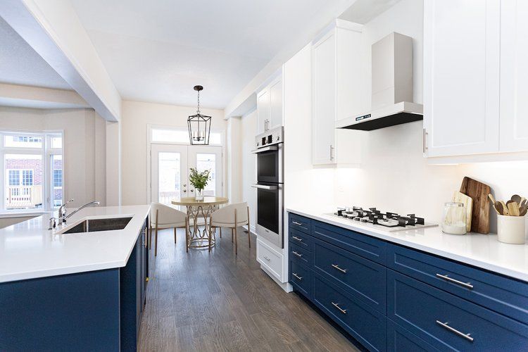 A kitchen with blue cabinets and white counter tops.