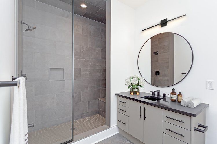 A bathroom with a walk in shower , sink and mirror.