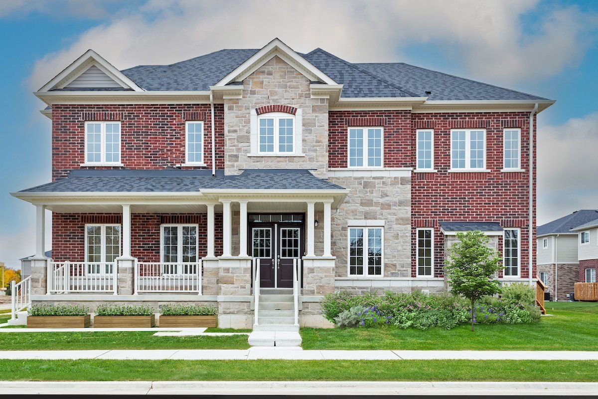 A large brick house with a blue roof is sitting on top of a lush green lawn.