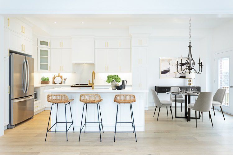 A kitchen with white cabinets , a stainless steel refrigerator , a table and chairs.
