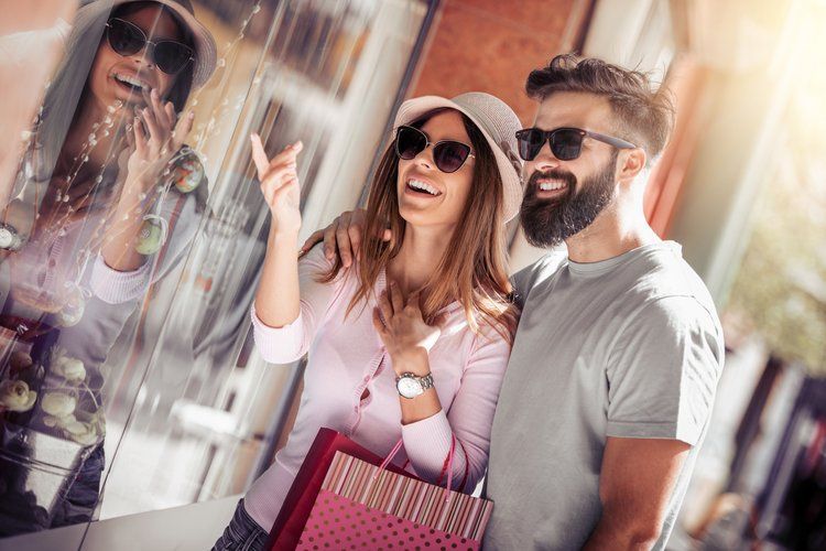 A man and a woman are standing next to each other in front of a store window.