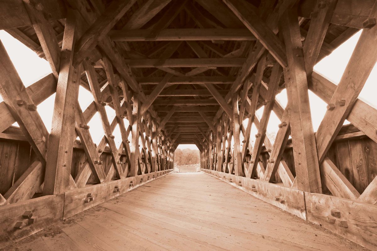 The inside of a wooden bridge with a road going through it