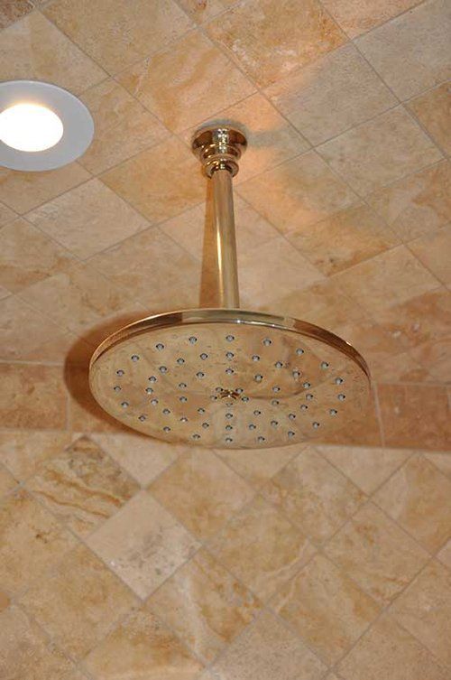 A shower head is hanging from the ceiling in a bathroom.