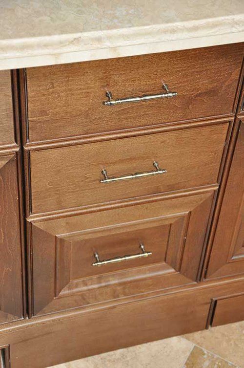 A close up of a wooden cabinet with three drawers