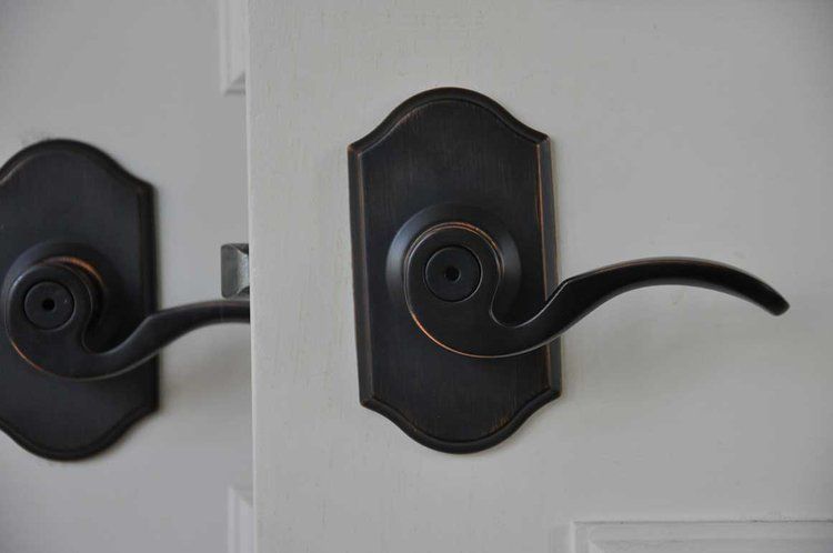 Two black door handles on a white door